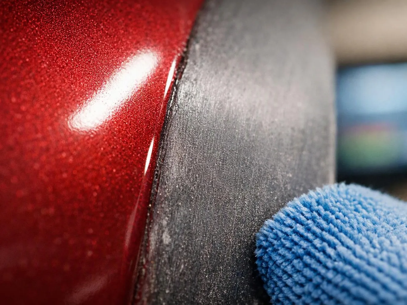 A blue microfiber cloth wipes a glossy red surface beside a dark textured panel