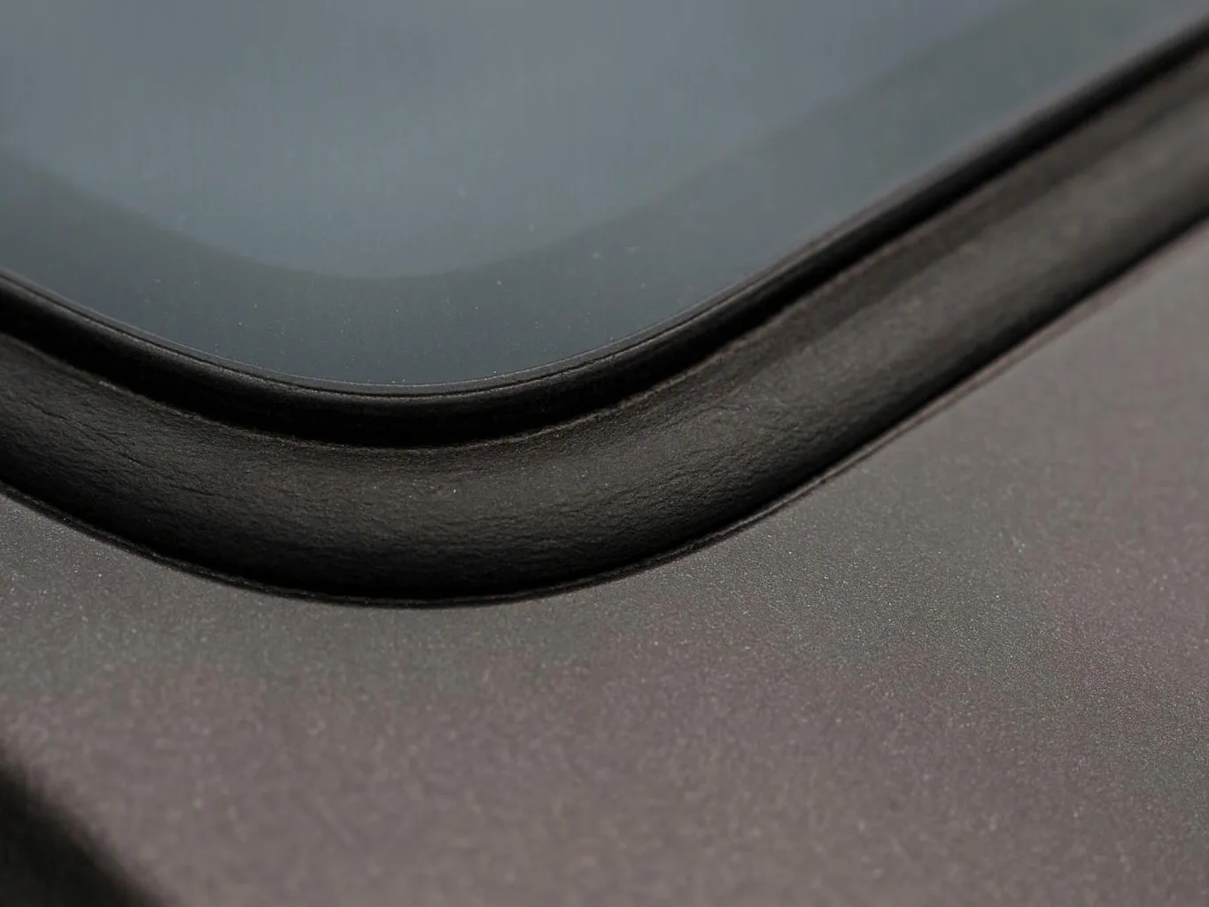 Close-up of a black glass screen set into a matte dark device surface