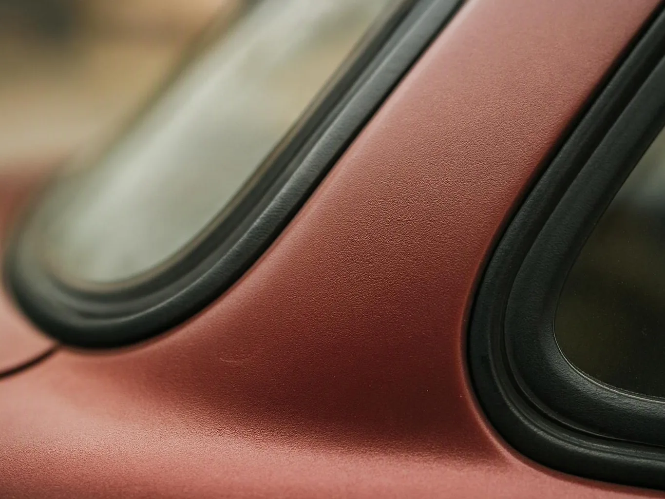 Close-up of a red car body with two rounded windows and black trim