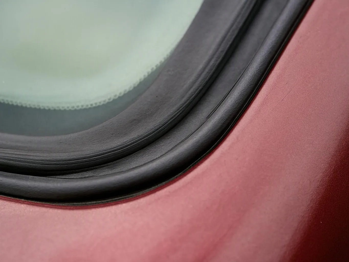 Close-up of a red vehicle window with black rubber trim and foggy glass inside