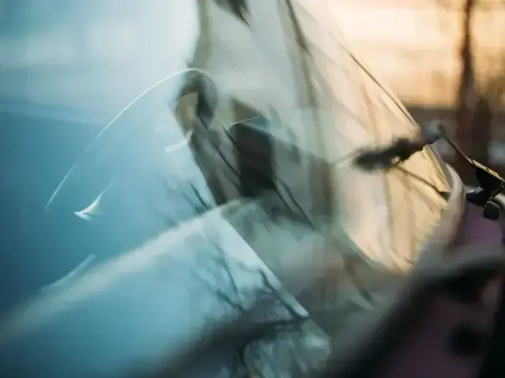 Close-up of resin injection into a windshield crack during repair in rainy Seattle weather